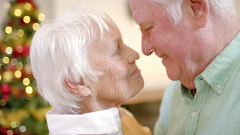 Happy-senior-caucasian-couple-dancing-next-to-christmas-tree-at-home,-slow-motion