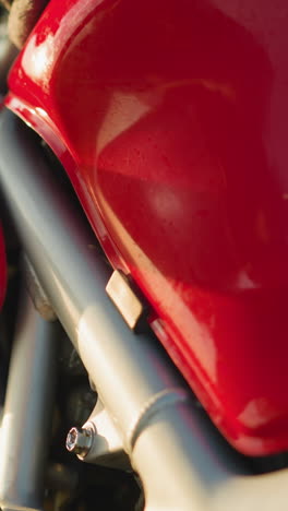 close-up of a hand carefully wiping the red and black fuel tank of a motorcycle with a cloth