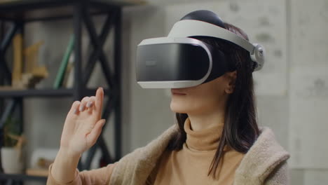 woman in a helmet of virtual reality against the background of a huge window in the office at the workplace. design engineer working in a virtual reality helmet.