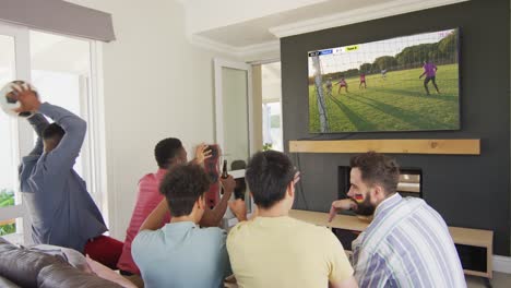 Video-Von-Verschiedenen-Freunden,-Die-Auf-Dem-Sofa-Sitzen-Und-Zu-Hause-Fußball-Im-Fernsehen-Schauen
