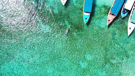 tourists enjoy swimming on the beach with fishing boats floating by the sea - beautiful tourist destination - aerial shot in philippines