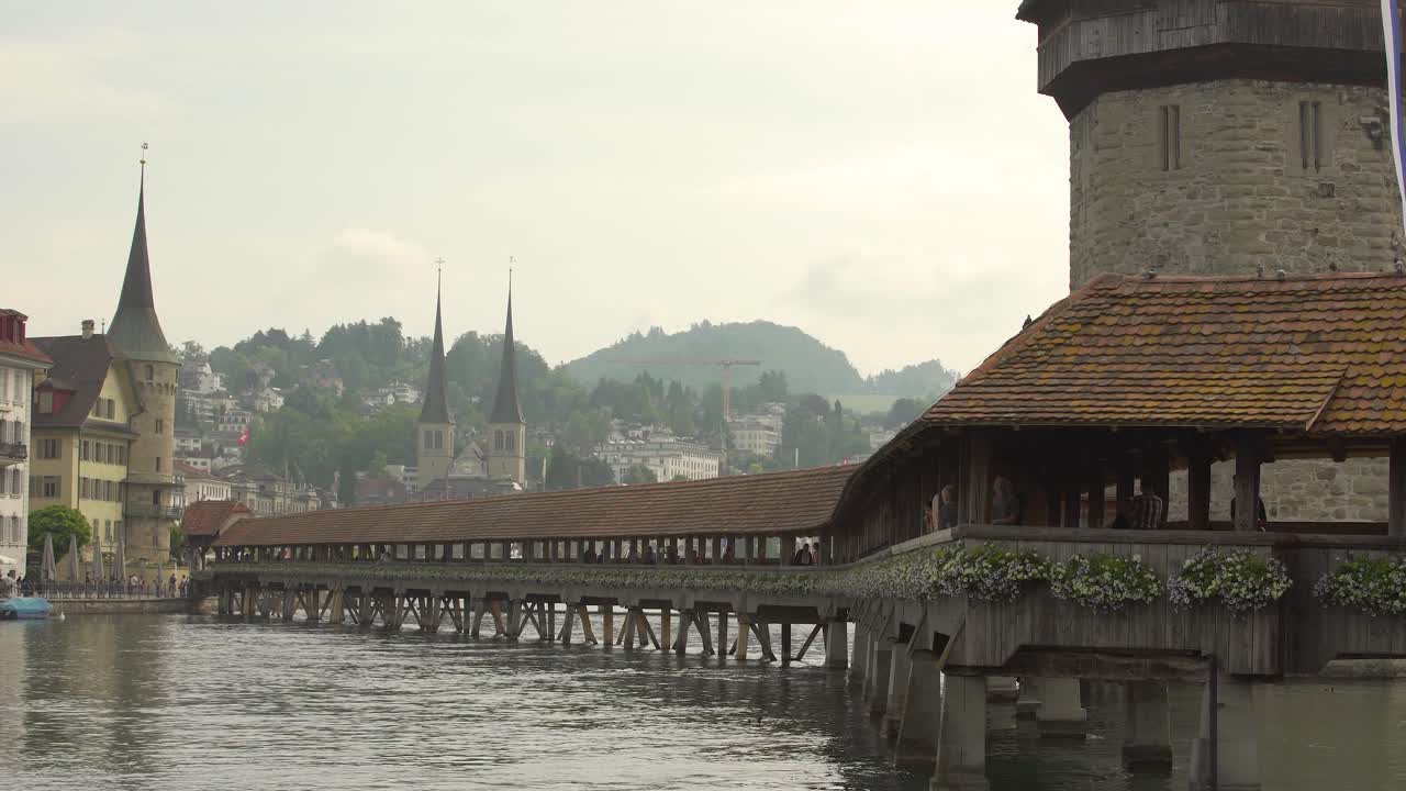 histórico puente kapellbrucke cubierto de madera y torre de agua en el río reuss, iglesia de san
