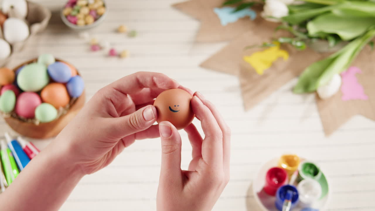 Hands Holding a Brown Easter Egg with a Smiley Face