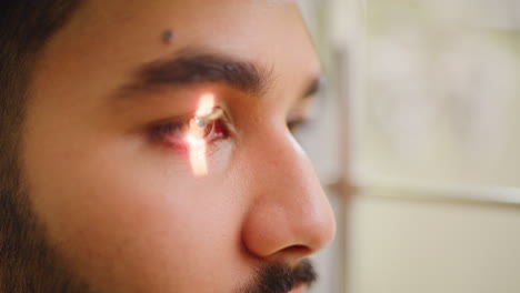 close-up of a man's face with sunlight reflecting in his eye