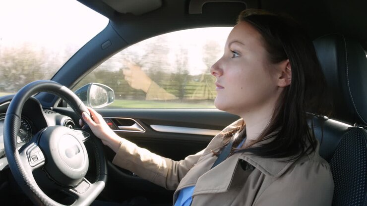 Giovane donna alla guida di un'auto, vista laterale