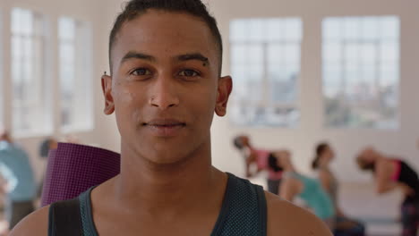 yoga class portrait of attractive mixed race man smiling confidently enjoying healthy lifestyle with multi ethnic people practicing in fitness studio background