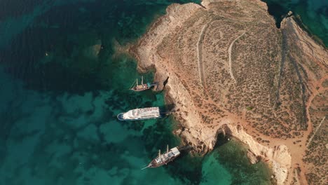 Aerial-tilt-down-reveal-drone-footage-of-Malta's-magnificient-Blue-Lagoon,-renowned-for-its-mesmerizing-clear-waters