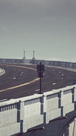 a curving concrete bridge with two lanes for cars.