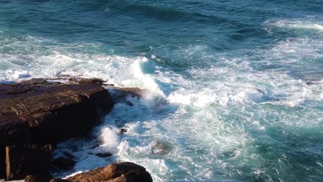 Aerial-view-of-Ocean-waves-flooding-on-rocky-shore,-showing-extreme-force-of-ocean