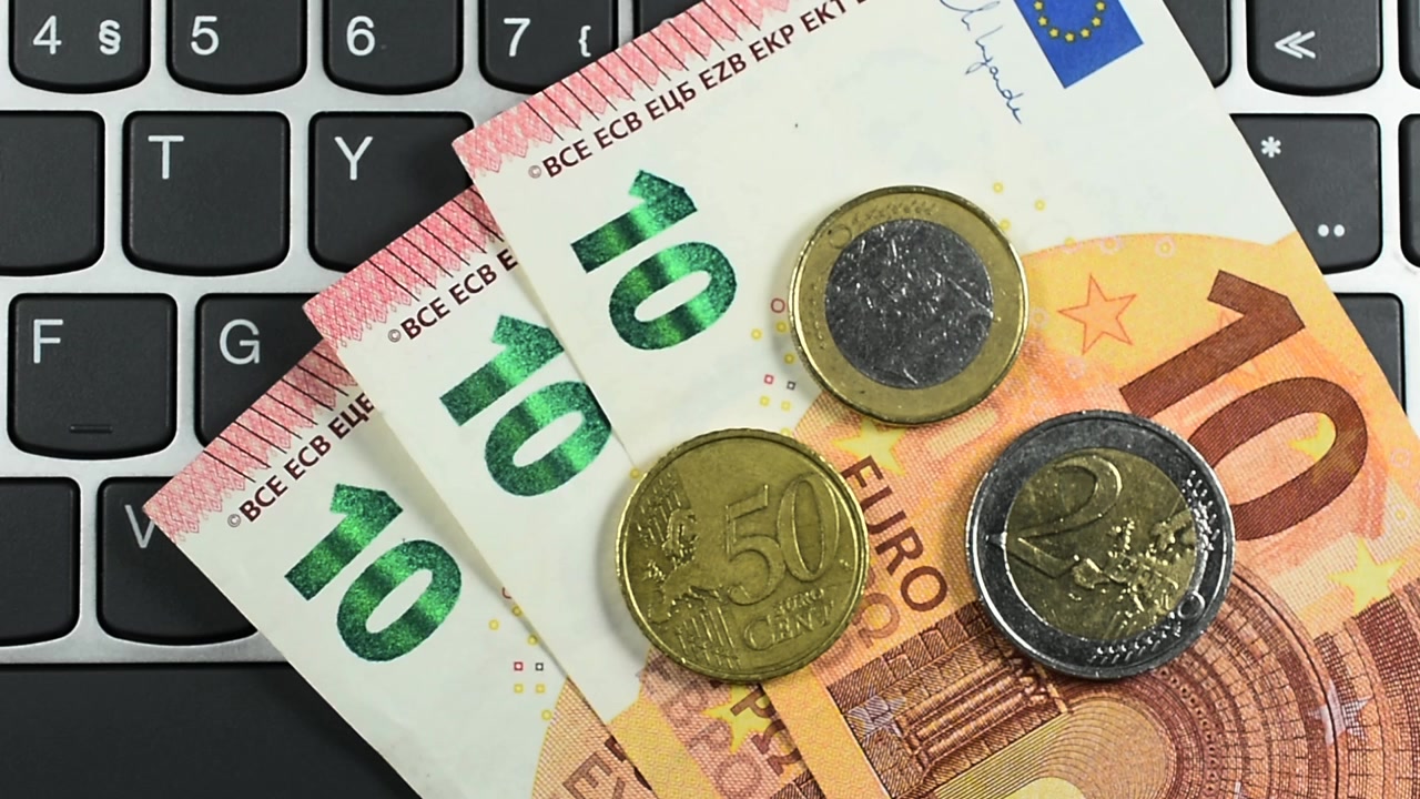 Banconote in euro su tastiera del computer, vista dall'alto