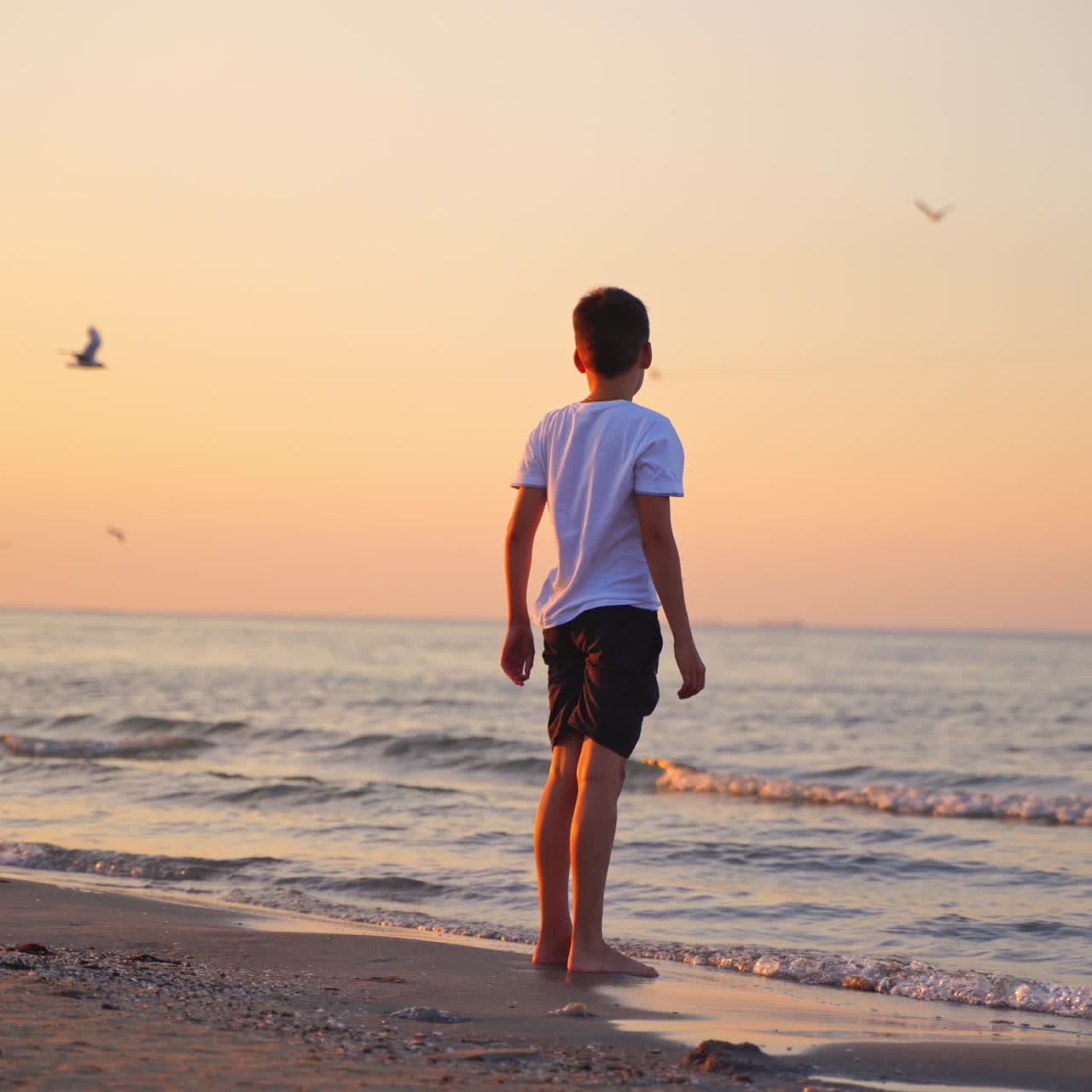 Cute boy and woman near the sea at sunset. Mother and her son having fun together on the evening sea water background.