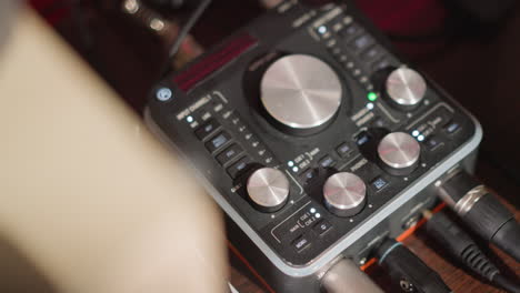 close-up shot of a sound mixer on a table in a recording studio, with various knobs and dials visible for controlling audio levels. emphasizing its use in professional audio production