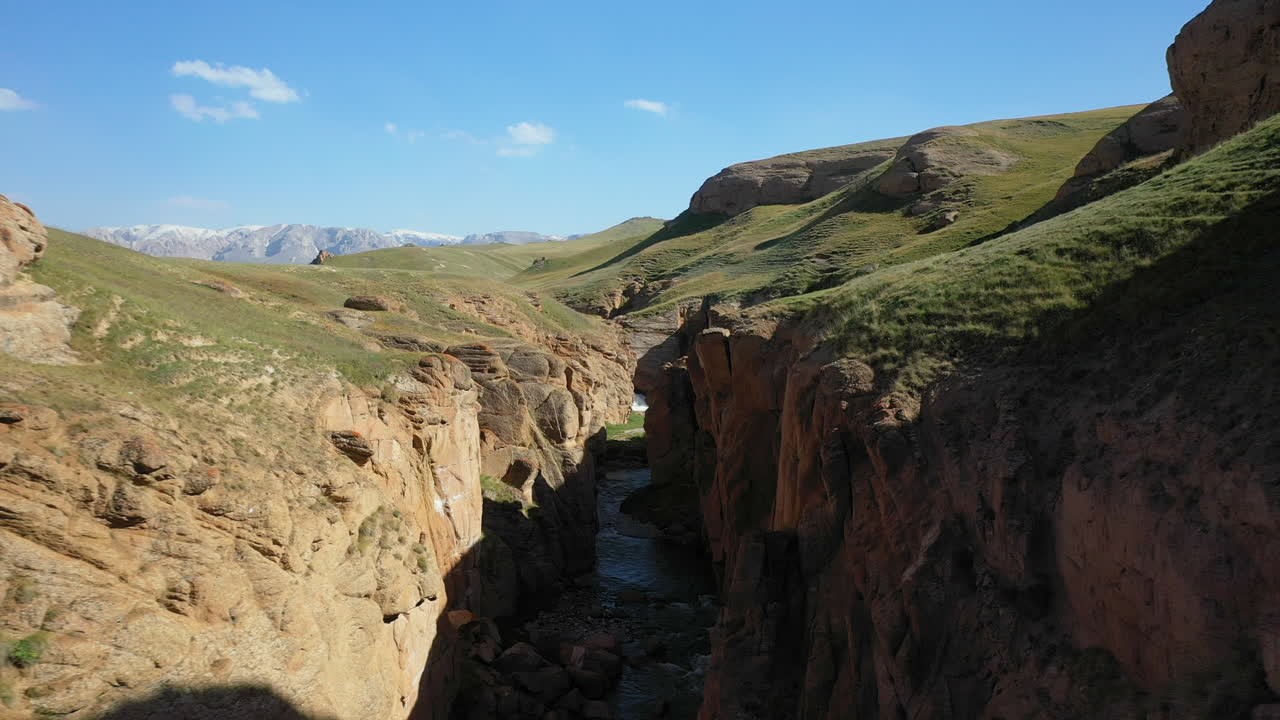 키르기스스탄의 켈수 호수 근처의 작은 강 근처 땅의 크레바스를 통과하는 장엄한 공중 드론 샷