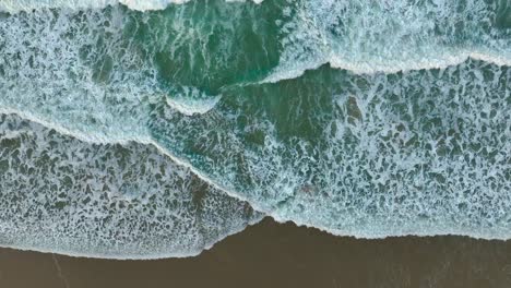 Olas-Espumosas-Salpicando-La-Orilla-Arenosa-De-La-Playa---Antena-Arriba-Hacia-Abajo