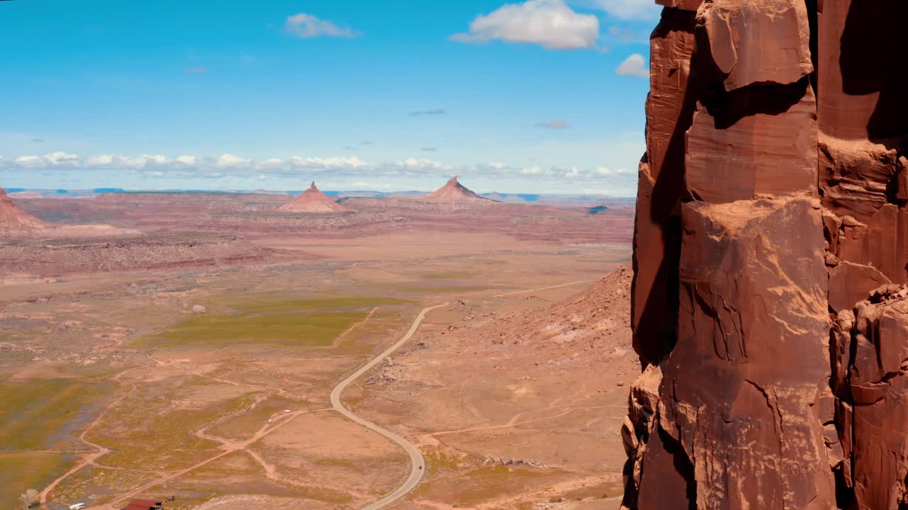 Drone aerial of Indian Creek Six Shooter Peaks emerging from rock wall in Bears Ears National Monument, Utah
