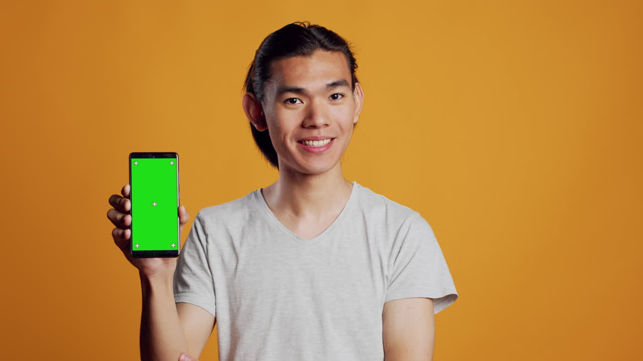 Asian male model showing smartphone with greenscreen