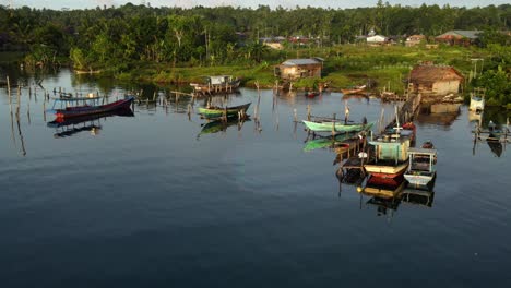 Coloridos-Pequeños-Barcos-De-Pesca-Tradicionales-Descansan-En-El-Puerto-De-Lahewa-Norte-De-La-Isla-De-Nias-Sumatra-Indonesia-Con-Paisaje-Verde-Y-Pueblo-Local-En-El-Fondo