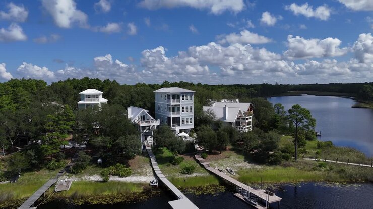 Dynamisk baglæns droneflyvning fra de moderne kystnære luksushuse omgivet af skovområde, 30A, Florida, USA.