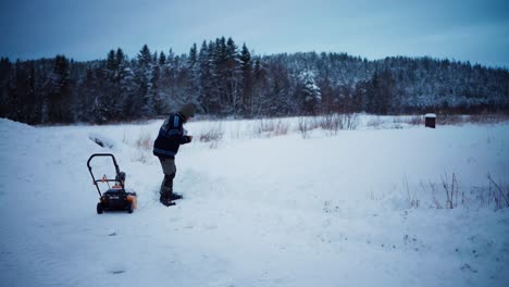 person working on winter landscape with snow blower and shovel