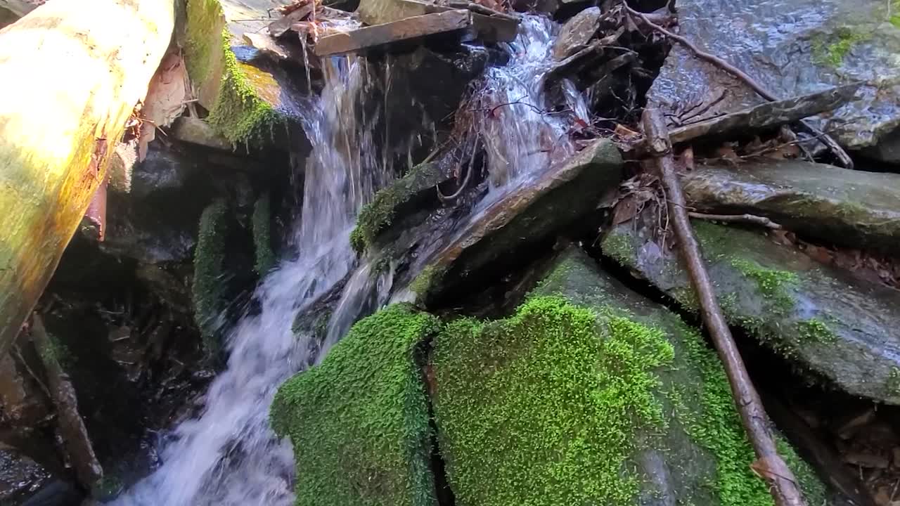 pan from left to right on a sunny day mountain waterfall