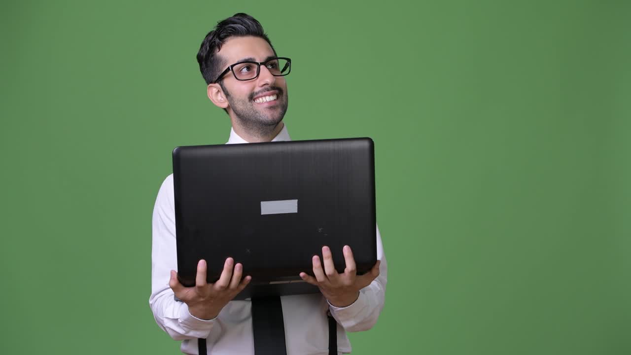 joven empresario persa barbudo y guapo contra un fondo verde