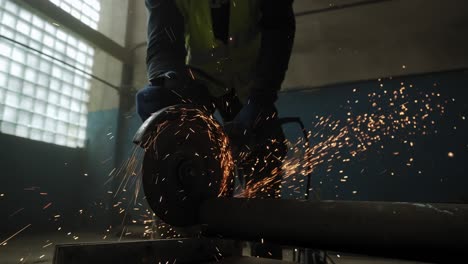 close up view of construction worker cuts steel with a circular saw, construction worker's feet, flying sparks from a circular saw. slow motion