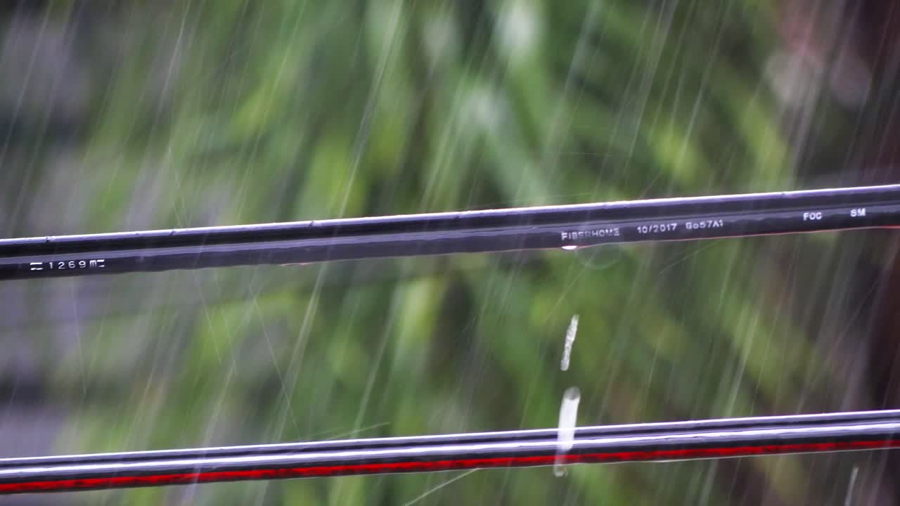 빗물 방울이 기둥 사이에 연결된 유틸리티 케이블의 길이를 따라 흐릅니다.