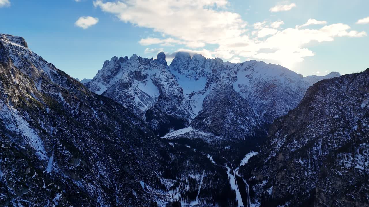 Valley in Italian Dolomites with breathtaking rock formation in the background (drone footage)