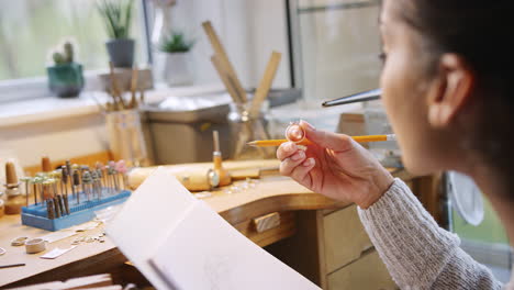 primer plano de una joyera dibujando el diseño de un anillo en el estudio