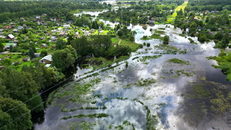 aerial view over a overgrown flooding river in middle of a community of homes