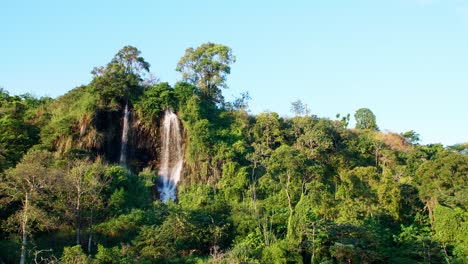 Ein-Weiter-Blick-Auf-Den-Natürlichen-Wasserfall,-Der-Den-Berg-Hinunterfließt,-Wird-Von-Der-Abendsonne-Beleuchtet