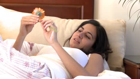 attractive brunette woman looking at a flower on sofa