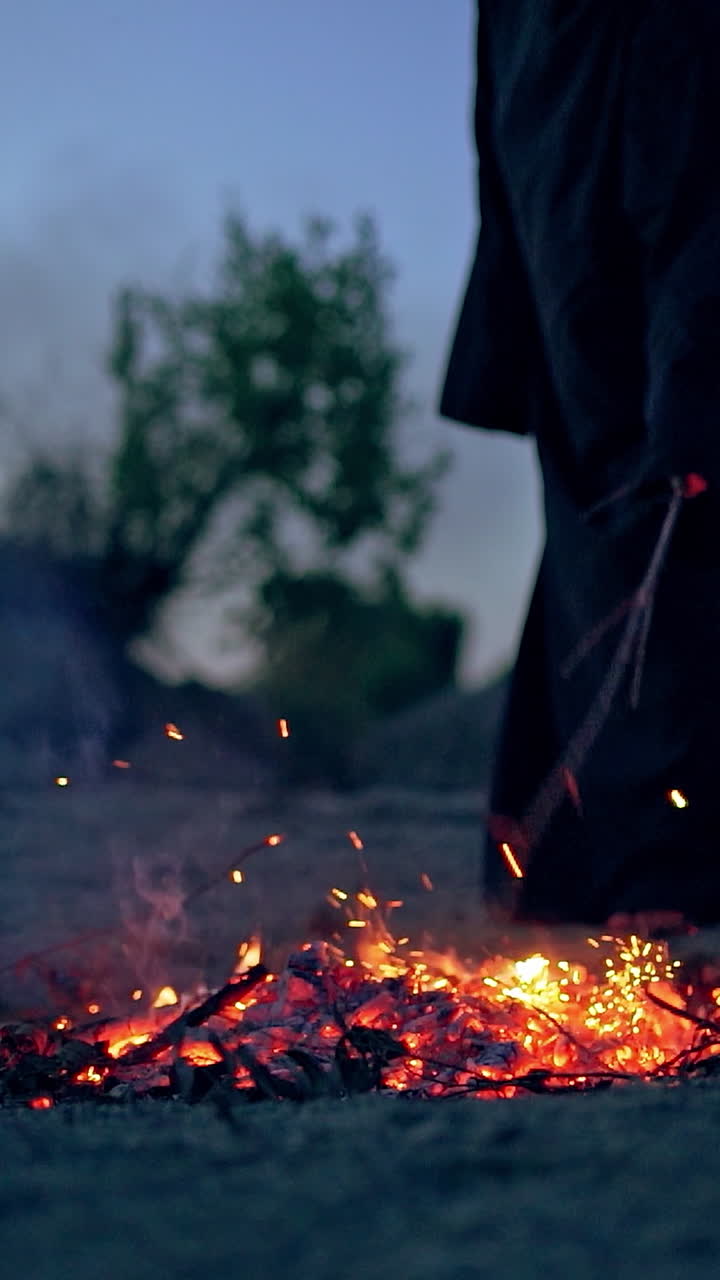 Witch in black near bonfire. Mystical witch walking around bonfire. Vertical video