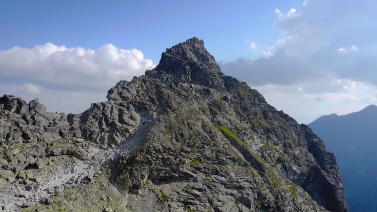 pico de montaña entre las nubes con un pequeño camino a la cima