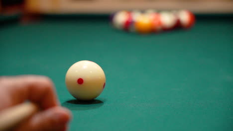 slow motion billiards low angle close up of cue ball as person breaks a rack of 8 ball on a pool table with green felt and the cue stick bending as both solid and stipe balls are contacted and skatter