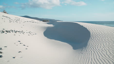 dunas de arena blanca con guijarros negros en el mar en porto pino, cerdeña, día luminoso