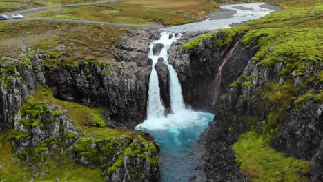 4K-drone,-aerial-cinematic-shots-of-a-vibrant-green-landscape-with-water-cascades-down-below-the-cliff-that-turns-into-a-blue-lagoon