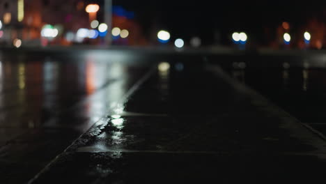 vista borrosa de coches con faros en una calle húmeda de la ciudad por la noche, creando vibrantes reflejos de luz en el pavimento