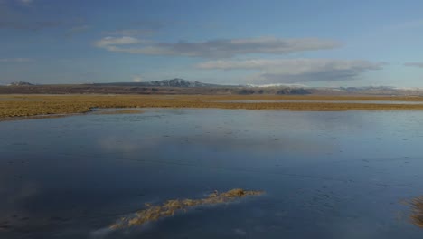 Fliegen-Sie-über-Die-Landschaft-Von-Feuchtgebieten-Mit-Fernen-Bergen-Im-Hintergrund-Am-Fluss-Olfusa-In-Der-Nähe-Von-Selfoss-In-Südisland