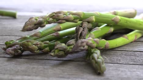 Footage-of-a-bunch-of-fresh,-green-asparagus-lying-on-a-wood-table