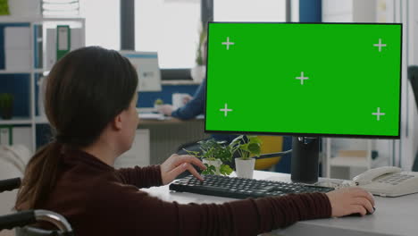 Immobilized-woman-working-on-desktop-computer-with-green-mock-up-screen