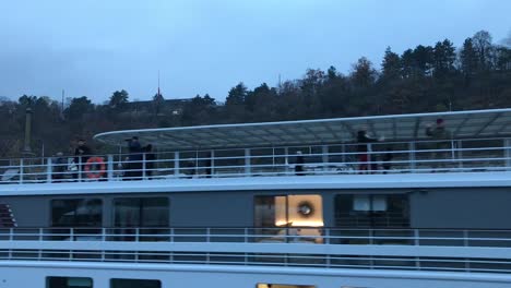 Closeup-of-passing-Vltava-river-cruise-ship-with-passengers-waving