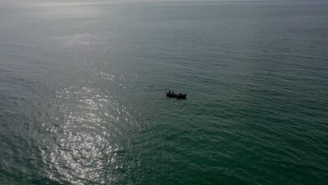 Vista-Aérea-De-La-Silueta-Del-Barco-Flotando-En-El-Mar-Arábigo-Con-Reflejo-De-La-Luz-Del-Sol