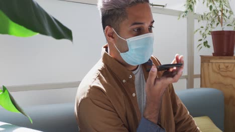 hombre con máscara facial hablando en un teléfono inteligente en la oficina
