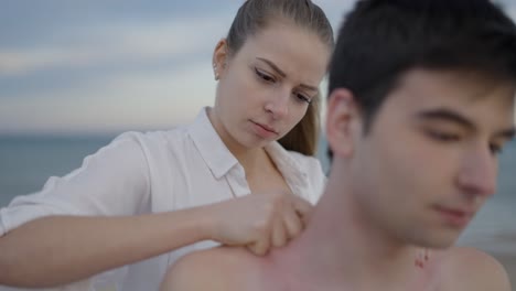woman massaging man's shoulder on the beach