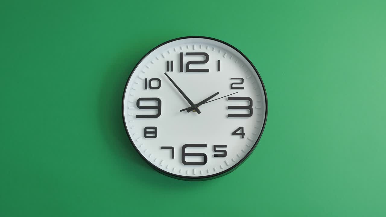 Orologio da ufficio bianco singolo appeso su sfondo verde.