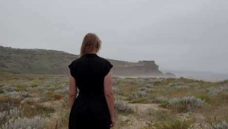 woman standing on a coastal cliff looking at the ocean