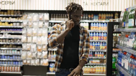 handsome man using smartphone, pushes shopping cart, walks at the store