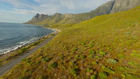 fpv drone flying fast next to the coastal road at kogel bay during sunset