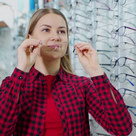 beautiful girl choosing new spectacles. smiling blonde woman trying on stylish eyeglasses in the optics store. eyewear concept.